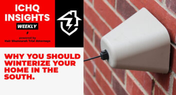 A cream-colored, cone-shaped outdoor electrical outlet cover is mounted on a red brick wall, with a black cable exiting the bottom.